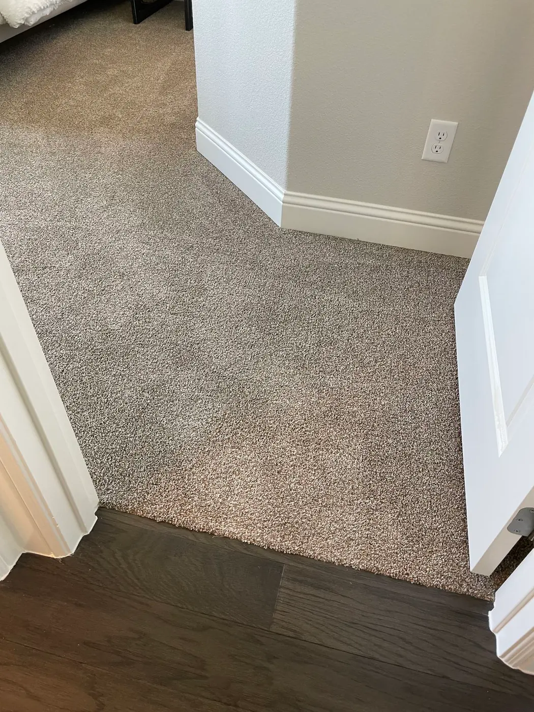 Close view of a light gray textured wall above white baseboard